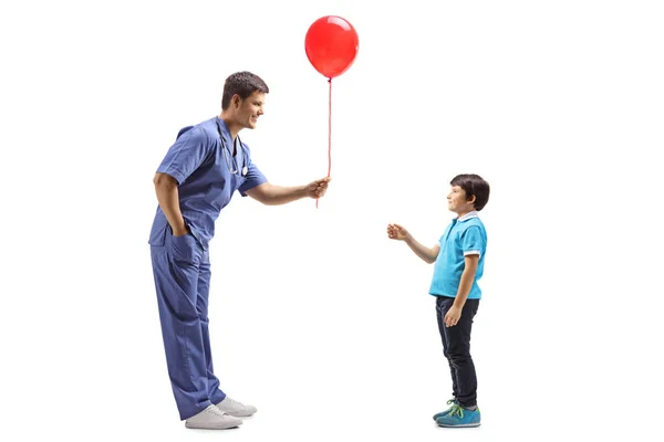 Doctor en uniforme azul dando un globo a un niño — Foto de Stock