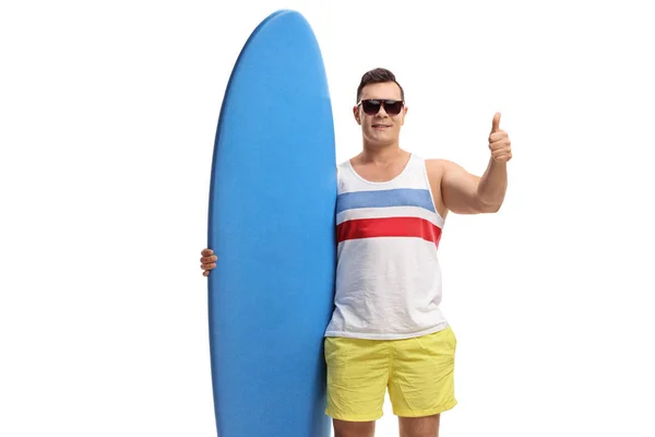 Молодой парень держит доску для серфинга и делает большой палец вверх жестом — стоковое фото
