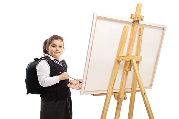 Schulmädchen malt auf Leinwand und blickt in die Kamera — Stockfoto