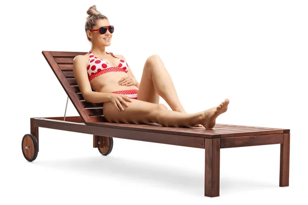 Giovane donna bionda attraente in bikini seduta su un lettino — Foto Stock