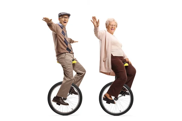 Ancianos hombre y mujer montando monociclos y sonriendo a la cámara — Foto de Stock