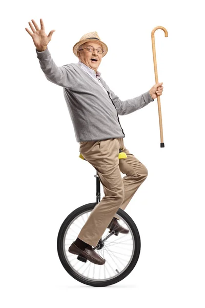 Hombre mayor montando una monociclo y sosteniendo un bastón —  Fotos de Stock