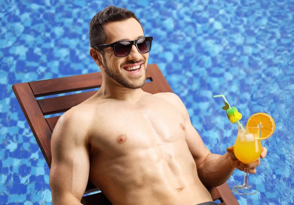 Handsome young man on a sunbed with a cocktail