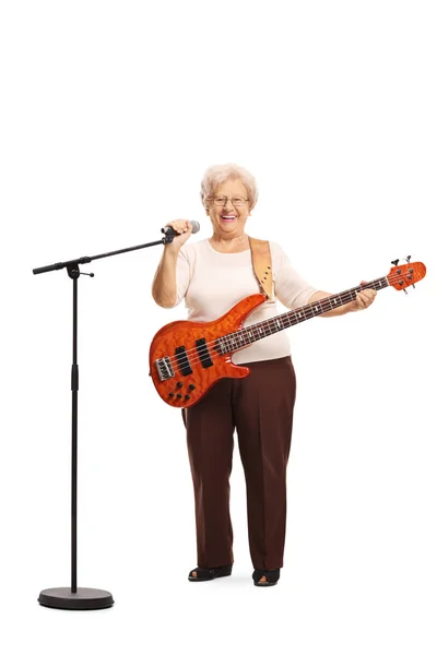 Elderly lady with a bass guitar holding a microphone — Stock Photo, Image