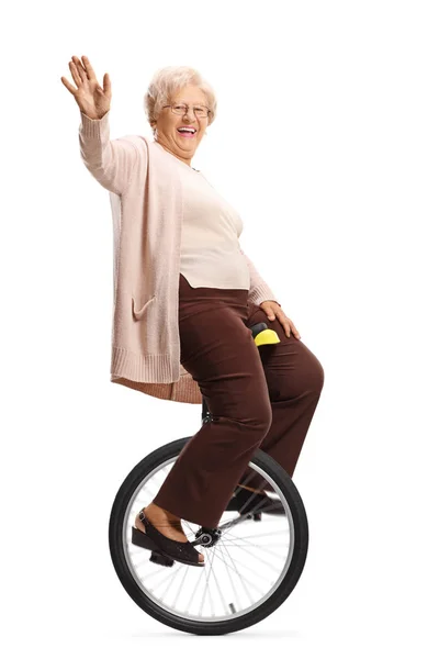 骑着独轮车的高级女人对着镜头挥手 — 图库照片