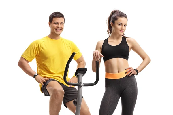 Guy on an exercise bike with a young woman in portswear — Stock Photo, Image