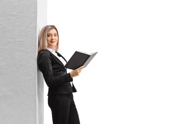 Businesswoman with a book leaning on a wall — Stock Photo, Image