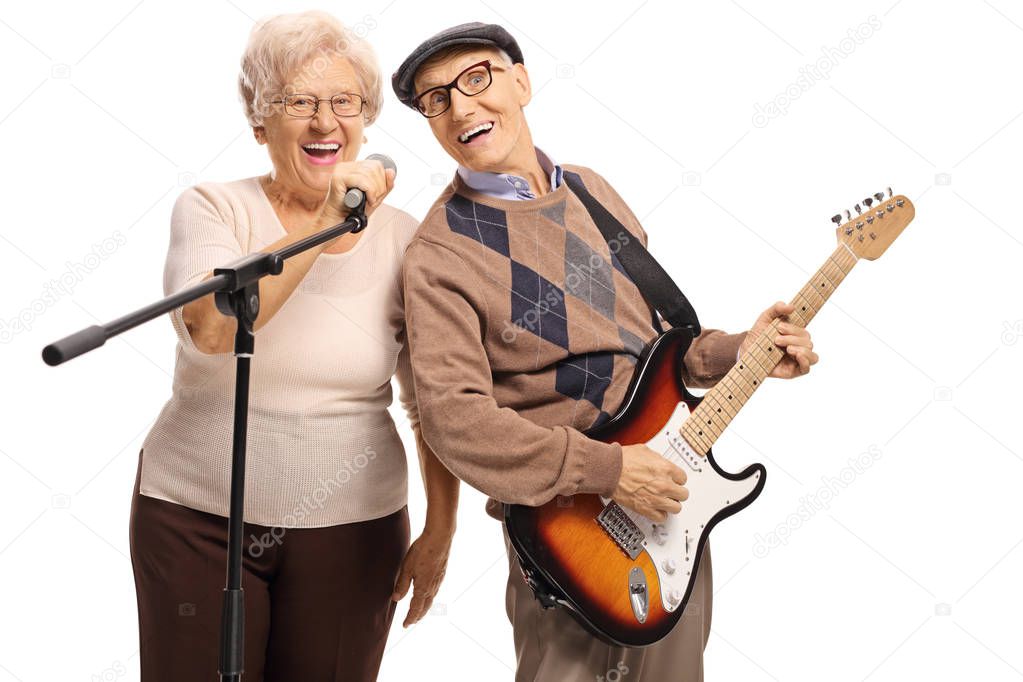 Senior man with an electric guitar and senior woman holding a mi