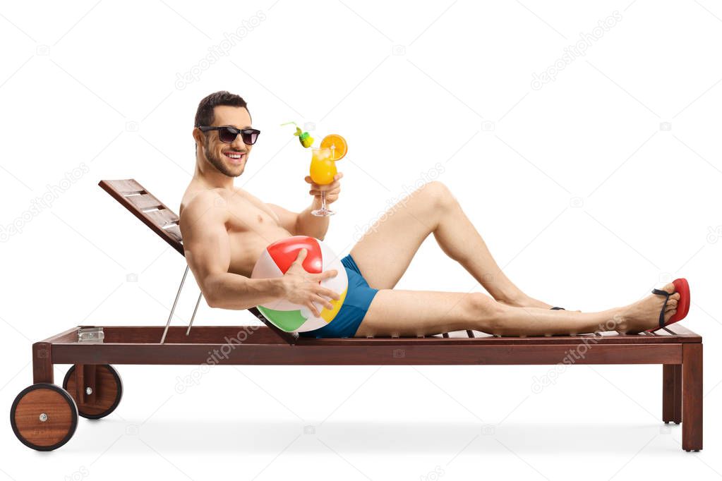 Guy on a lounge bed holding an inflatable ball and a cocktail 