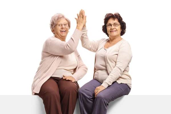 Ancianos frends femeninos sentados en un panel chocando unos con otros — Foto de Stock