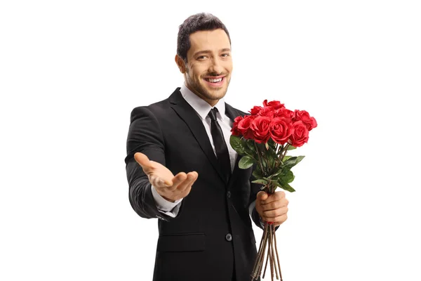 Guapo joven con un traje sosteniendo un montón de rosas rojas y sh —  Fotos de Stock