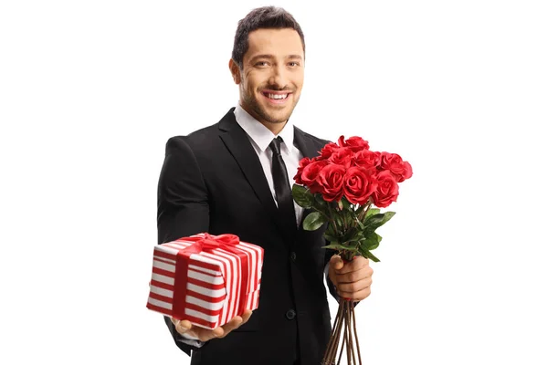 Joven hombre elegante sosteniendo rosas y un regalo —  Fotos de Stock