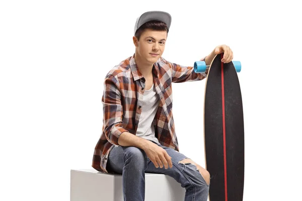 Adolescent garçon avec un longboard assis — Photo