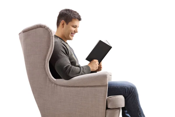Junger Mann im Sessel liest ein Buch — Stockfoto
