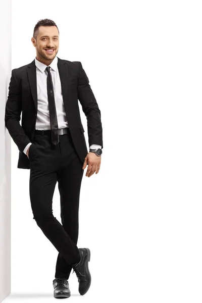 壁に寄りかかっている黒いスーツを着た若い陽気な男 — ストック写真