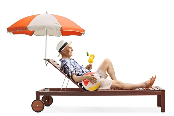 Senior man on a sunbed with a ball and a cocktail — Stock Photo, Image
