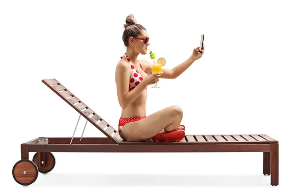 Giovane donna in bikini seduta su un lettino con cocktail e t — Foto Stock