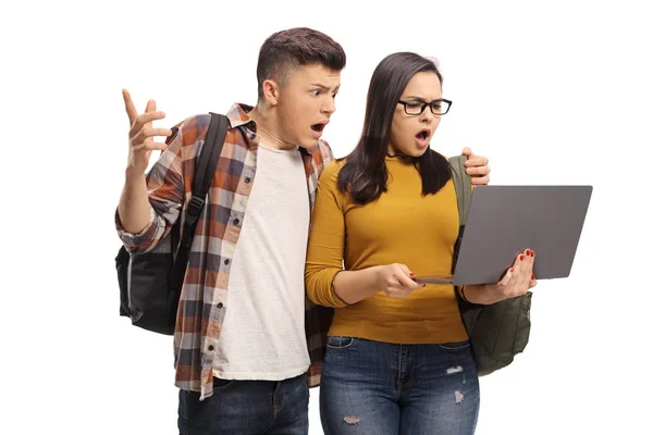 Male and female surprised students looking in a laptop — Stock Photo, Image