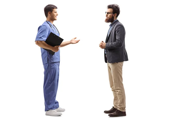 穿蓝色制服的男医生与一个留着胡子的男人交谈 — 图库照片