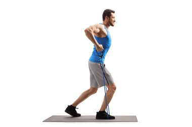 Bir direnç bandı ile genç adam bir paspas üzerinde egzersiz