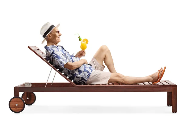 Senior man relaxing on a beach bed with a cocktail — Stock Photo, Image