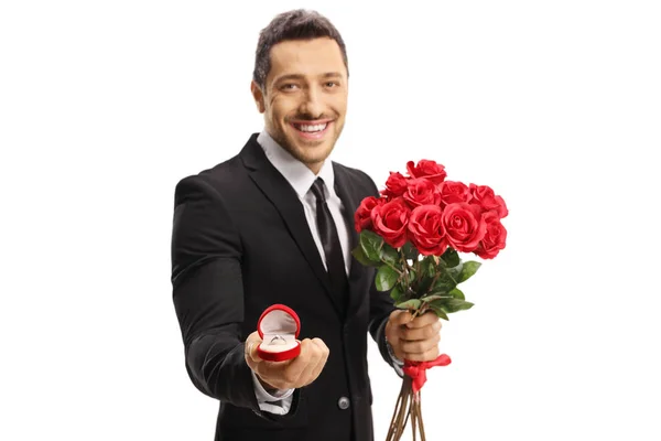 Un tipo guapo con un traje sosteniendo un ramo de rosas y un anillo en —  Fotos de Stock