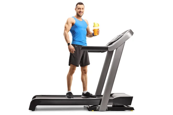 Muskularny Człowiek stoi na bieżni i trzyma filiżankę sportu — Zdjęcie stockowe