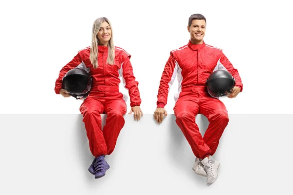 身着红色制服的男女赛车手坐在面板上 — 图库照片