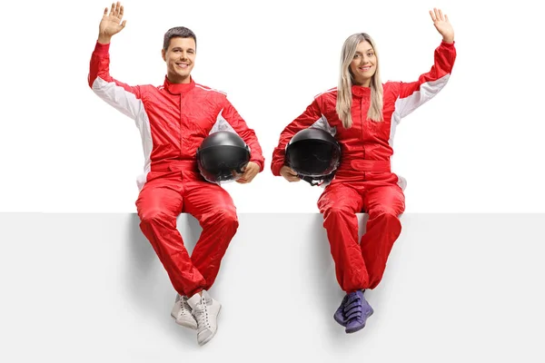 Male and female car racers sitting on panel and waving — Stock Photo, Image