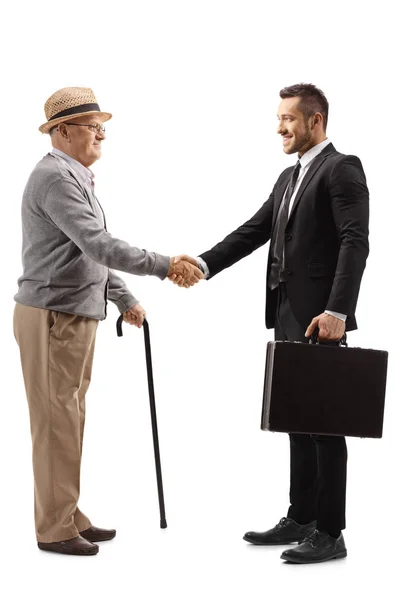 Пожилой джентльмен пожимает руку молодому человеку в костюме с — стоковое фото