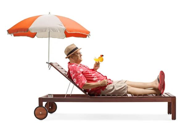 Matura maschio turista in possesso di un cocktail e rilassante sotto l'ombrello — Foto Stock