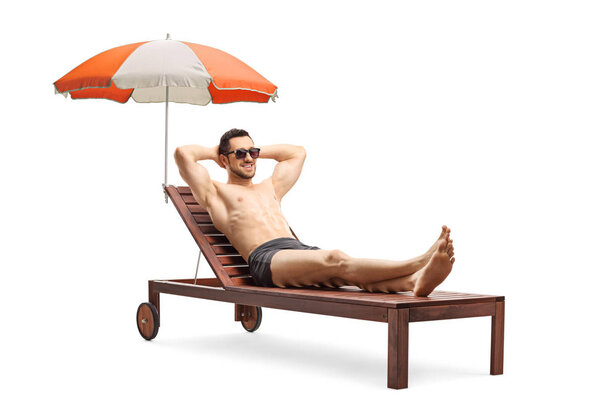 Young man lying on a sunbed under umbrella