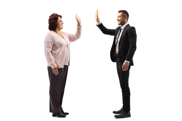 Senior vrouw gebaren hoog-vijf met een jonge man in een pak — Stockfoto
