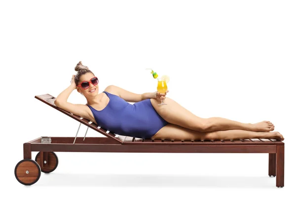 Attractive blond woman with sunglasses lying on a sunbed and hol — Stock Photo, Image