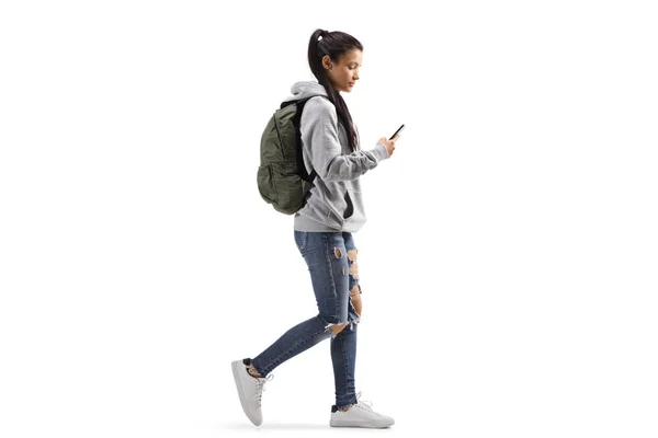 Female student with a backpack walking and looking into a mobile — Stock Photo, Image