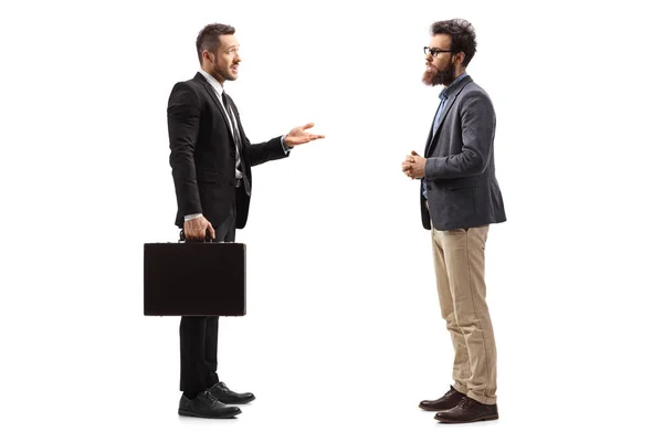 Молодий бізнесмен з валізою, що пояснює бородатому чоловікові — стокове фото