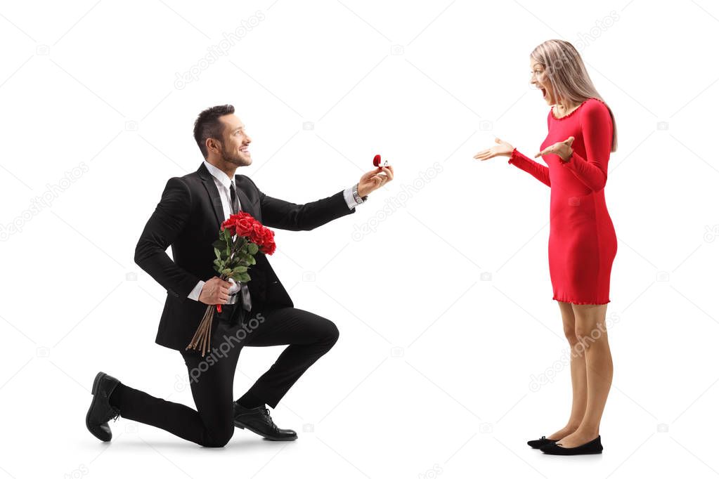 Young man kneeling with roses and an engagement ring and proposi