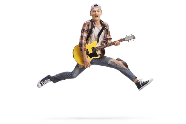 Young male musician playing an electric guitar and jumping — Stock Photo, Image