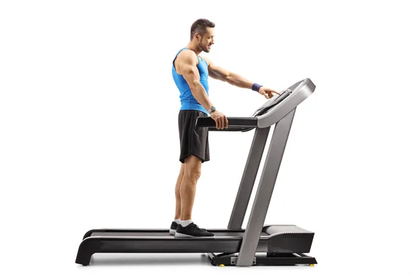 Muscular man turning on treadmill — Stock Photo, Image