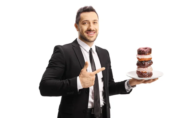 Empresário segurando um prato de donuts de chocolate e apontando — Fotografia de Stock