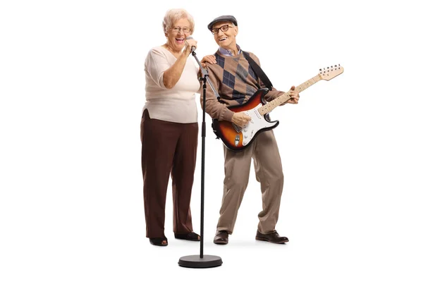 Mujer mayor cantando en un micrófono y un caballero anciano p — Foto de Stock