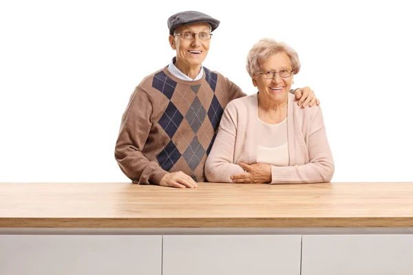Homem idoso e mulher posando atrás de um balcão de madeira — Fotografia de Stock