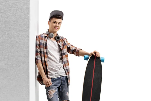 Joven chico hipster con un longboard apoyado contra la pared —  Fotos de Stock