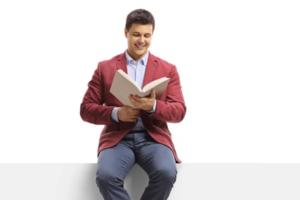 Jonge man zittend op een panel en het lezen van een boek — Stockfoto