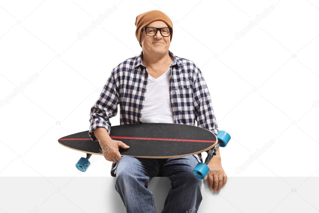 Mature man with a longboard sitting on a panel 