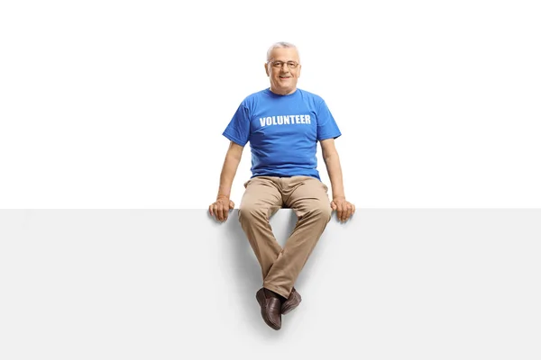 Mature volunteer sitting on white panel and smiling at the camer — Stock Photo, Image