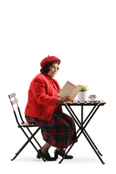 Elderly lady at a cafe table reading a book — Stock Photo, Image