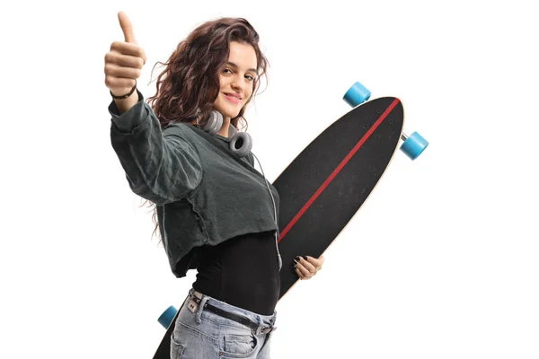 Joven hembra con un longboard mostrando pulgares hacia arriba — Foto de Stock