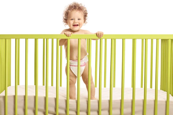 Lachende schattige baby staande in een babybedje — Stockfoto