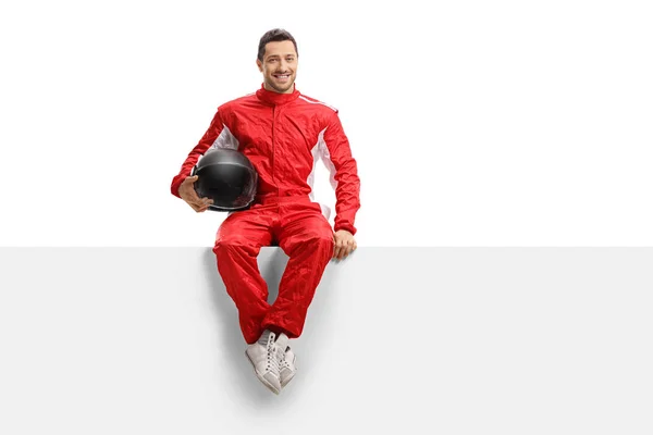 Racer in een rood uniform zittend op een panel met een helm en s — Stockfoto